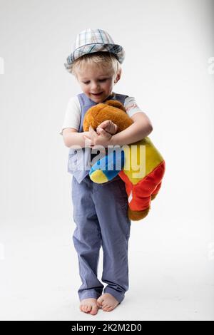 petit bébé avec chapeau qui embrasse son ours en peluche Banque D'Images