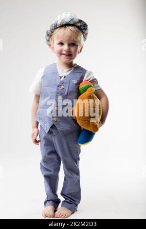 petit bébé avec chapeau qui embrasse son ours en peluche Banque D'Images