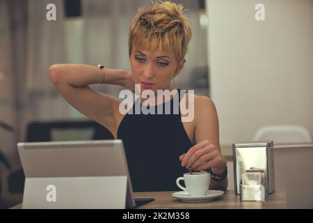 Femme prenant un café dans une cafétéria car elle utilise une tablette pc Banque D'Images