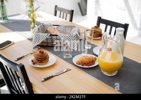 crêpes savoureuses près des croissants cuits, boissons et smartphone avec écran vierge sur la table, image de stock Banque D'Images