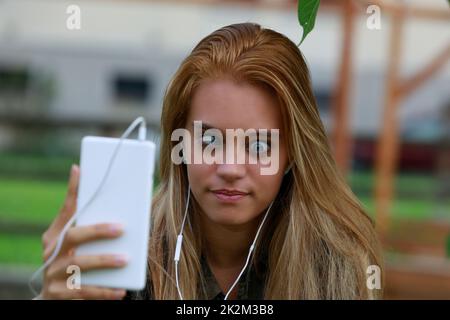 fille fait des visages drôles et des yeux mal à l'aide de son téléphone portable Banque D'Images