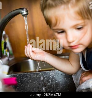 petite fille avec sa main sous l'eau Banque D'Images