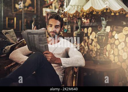 Obtenir mon correctif quotidien de mon café préféré. Portrait d'un beau homme lisant un journal dans un café. Banque D'Images