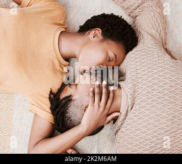 Chaque baiser est comme le premier. Photo aérienne d'un jeune couple qui embrasse à la maison. Banque D'Images