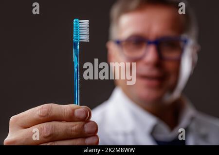 Gros plan de la main d'un dentiste montrant une brosse à dents bleue Banque D'Images