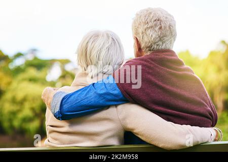 Engagé dans une vie d'amour.Vue arrière d'un couple senior assis sur une banquette de parc. Banque D'Images