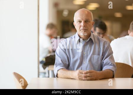 Un homme senior assis regarde calmement Banque D'Images