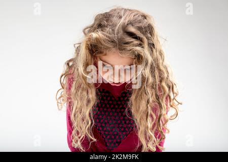 Triste écolière aux cheveux bouclés, tête en bas Banque D'Images