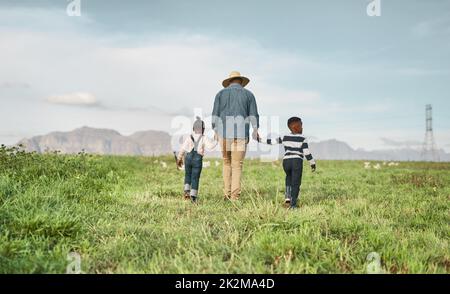 À la fin de la journée sa famille qui compte. Vue arrière d'un homme et de ses deux adorables enfants explorant une ferme. Banque D'Images