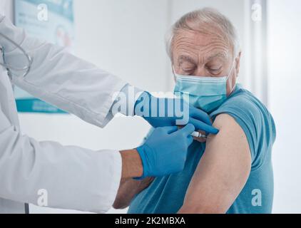 Obtenir le jab. Injection de vaccin contre le covid 19 réalisée par un beau homme âgé. Banque D'Images