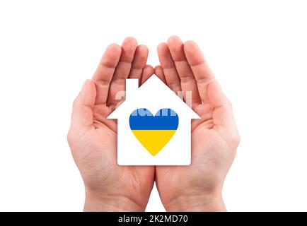 Maison en papier avec coeur ukrainien découpé dans les mains isolées sur fond blanc avec chemin de coupure. Banque D'Images