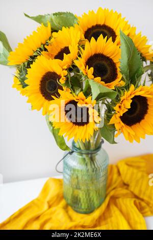 Un beau bouquet de tournesols est placé dans un vase sur la table. Fleurs. Bouquet d'anniversaire ou de mariage dans un style rustique. Banque D'Images