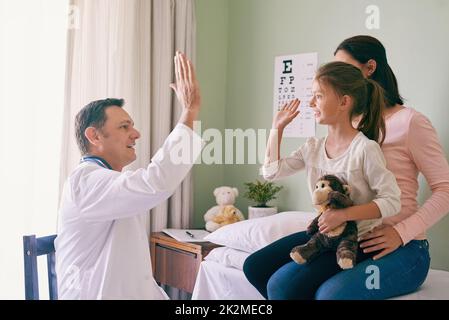 Cinq hauts pour une petite fille courageuse. Prise de vue d'un médecin donnant à son jeune patient un haut cinq après son examen. Banque D'Images