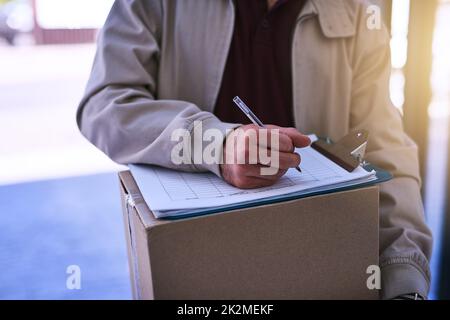 Votre colis est en route en toute sécurité. Photo rognée d'un coursier non identifiable remplissant les documents administratifs pendant une livraison. Banque D'Images