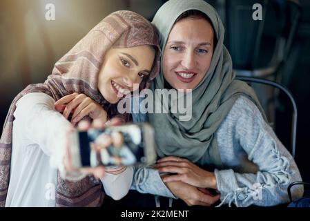 Ce n'est pas un rattrapage jusqu'à ce que vous prenez un selfie. Photo de deux femmes prenant des selfies avec un téléphone portable dans un café. Banque D'Images