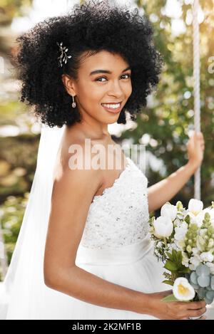 Je suis à quelques pas de mon pour toujours. Portrait d'une jeune mariée heureuse et belle tenant un bouquet de fleurs tout en posant à l'extérieur le jour de son mariage. Banque D'Images