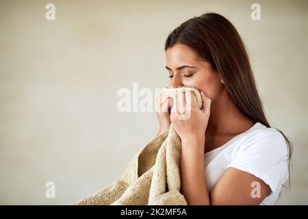 Doux et frais. Prise de vue d'une jeune femme qui apprécie l'odeur des serviettes fraîchement lavées. Banque D'Images