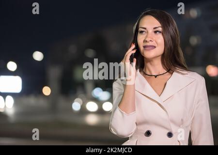 Une femme d'affaires adulte parle avec un ami par téléphone dans la rue Banque D'Images