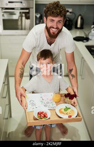 Les mamans vont être si surpris. Photo d'un adorable petit garçon tenant un plateau de petit déjeuner avec son père pour la fête des mères. Banque D'Images