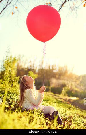 J'aimerais que cela me vole vers le ciel. Photo d'une jeune fille jouant avec un ballon à l'extérieur. Banque D'Images