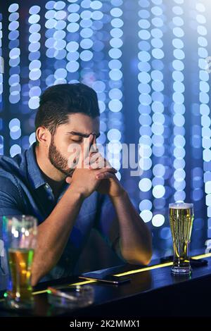 Une autre nuit d'enfer ne jamais revenir. Photo d'un jeune homme qui regarde stressé tout en prenant un verre au bar seul. Banque D'Images