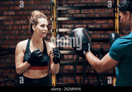 Allez, allez-y. Coupe courte d'un joli boxer féminin s'entraîner avec son entraîneur personnel dans une salle de sport. Banque D'Images