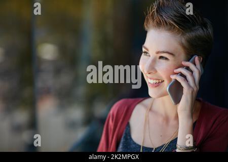 C'est juste l'actualité que j'attendais. Photo d'une jeune femme d'affaires attirante utilisant son téléphone portable tout en se tenant sur le balcon de son bureau. Banque D'Images