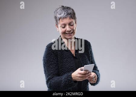 Femme sénior qui tape sur son mobile Banque D'Images