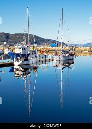 Les bateaux à voile se reflètent dans l'eau calme de Trondheim, en Norvège Banque D'Images