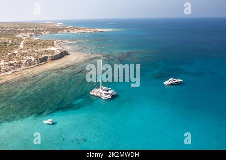 Vue aérienne de trois bateaux sur l'eau claire d'azur près de la côte rocheuse (Chypre) Banque D'Images