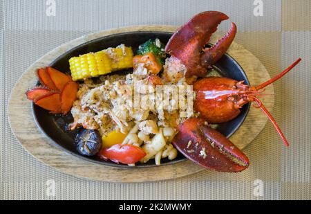 Steak de homard de style japonais servi sur une poêle chaude avec des légumes beurrés comme accompagnement. Vue de dessus Banque D'Images