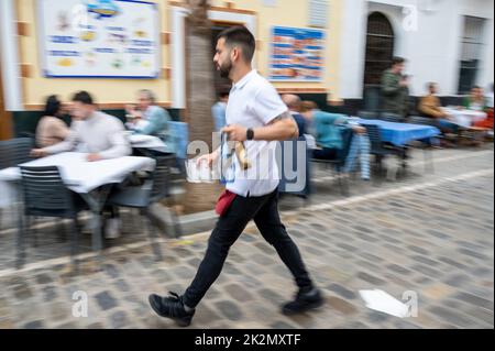 Une image abstraite floue d'un serveur servant des tables à l'extérieur dans la rue de Cadix Espagne avec le flou de mouvement Banque D'Images