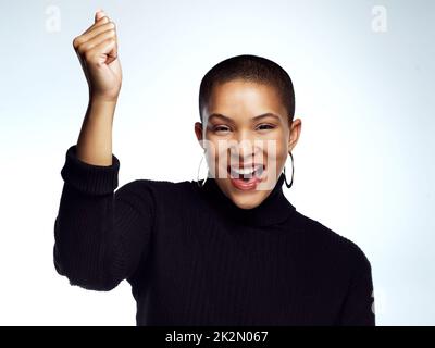 Envoyez un message instantané à votre plus grand supporter. Photo en studio d'une jeune femme attrayante posant avec son bras levé et poing rabattus sur un fond gris. Banque D'Images