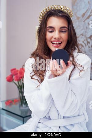 Réveil et maquillage. Photo d'une jeune femme attrayante appliquant un rouge à lèvres à la maison. Banque D'Images