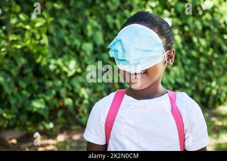 Est-ce un masque oculaire. Photo d'une petite fille couvrant ses yeux avec un masque dans la nature. Banque D'Images