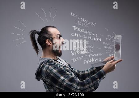 Homme barbu réagissant avec horreur à un Tablet pc Banque D'Images