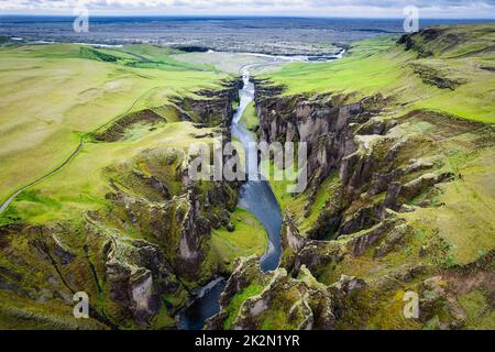 Vue aérienne magnifique de la mousse sauvage Fjadlargjufur canyon avec Fjadra qui coule à travers en été au sud-est de l'Islande Banque D'Images