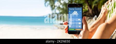 Femme utilisant Smart Home sur un téléphone portable à Beach Banque D'Images