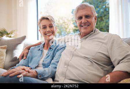 Couple, amour et retraite avec un homme et une femme âgés assis ensemble dans le salon de leur maison. Heureux, sourire et affection avec une personne âgée Banque D'Images