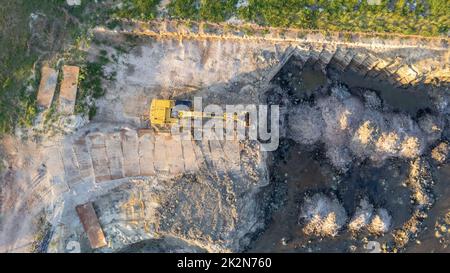 Le bulldozer à chenilles jaunes effectue des travaux de terrassement - vue aérienne. Un tracteur à chenilles jaune ratisse le sol pour construire une route asphaltée. Le bulldozer en terre travaille pendant la construction de la route. Photo de haute qualité Banque D'Images