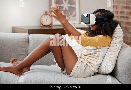 Tout le monde a besoin d'échapper à ce monde. Photo d'une jeune fille jouant avec un casque vr à la maison. Banque D'Images