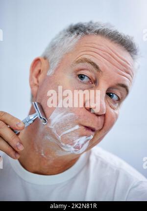 Je dois me concentrer lors du rasage. Photo d'un homme mûr se rasant le visage dans une salle de bain à la maison. Banque D'Images