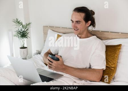 Homme avec ordinateur portable dans le lit. Banque D'Images
