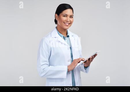 La technologie simplifie la science. Portrait rogné d'une jeune scientifique attrayante utilisant une tablette en studio sur un fond gris. Banque D'Images