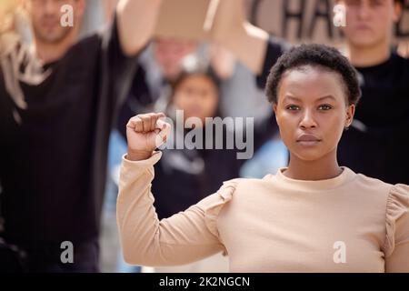 Dédié à la cause. Coup de feu d'une jeune femme avec son poing élevé en solidarité lors d'une marche. Banque D'Images