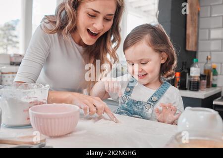 Vous, comme le cuisinier, devez apporter l'âme à une recette. Photo d'une mère et d'une fille qui cuit dans la cuisine à la maison. Banque D'Images