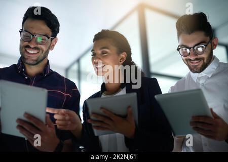 S'occuper des affaires numériques.Prise de vue de trois collègues utilisant des tablettes numériques dans un bureau. Banque D'Images