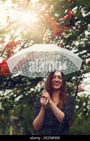 Certaines personnes regardent la pluie et les frondes, pas elle. Photo courte d'une belle jeune femme marchant sous la pluie à l'extérieur. Banque D'Images