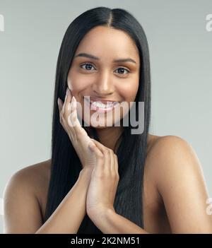 Prendre soin de votre peau est vraiment payant. Photo courte d'une belle jeune femme avec une peau impeccable posé sur un fond gris. Banque D'Images