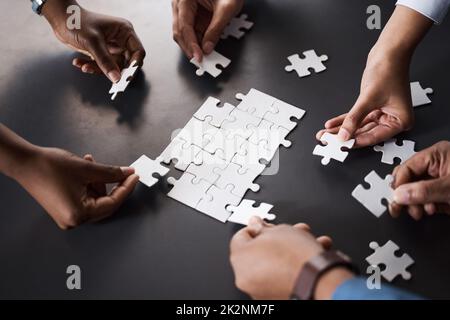 La résolution des problèmes en tant qu'équipe dédiée devrait. Gros plan d'un groupe d'hommes d'affaires méconnus qui ont joint des pièces de puzzle dans un bureau. Banque D'Images